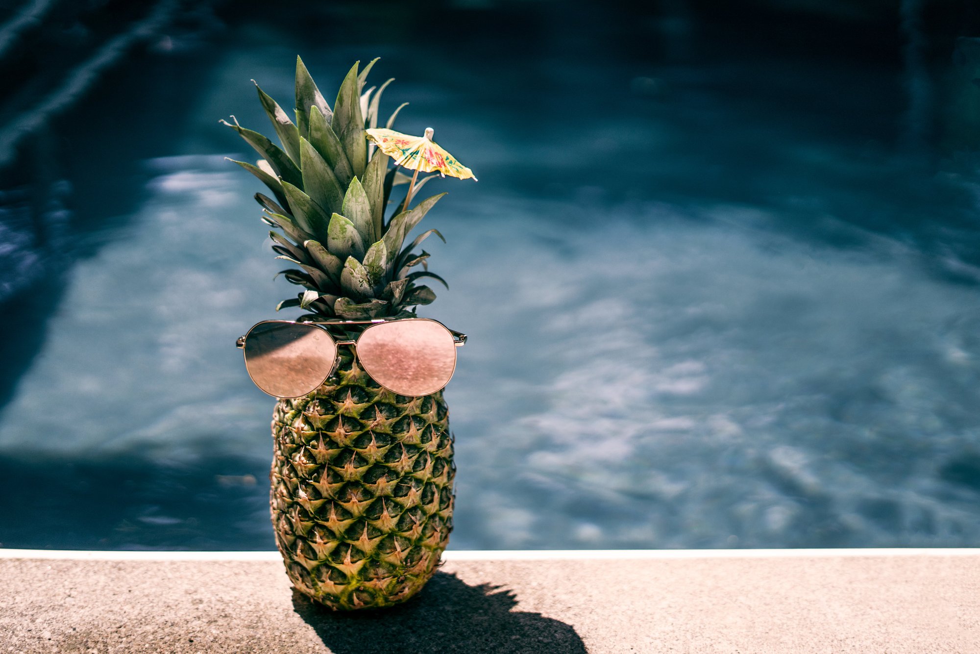 Bild mit einer Ananas am Strand vor dem Meer.